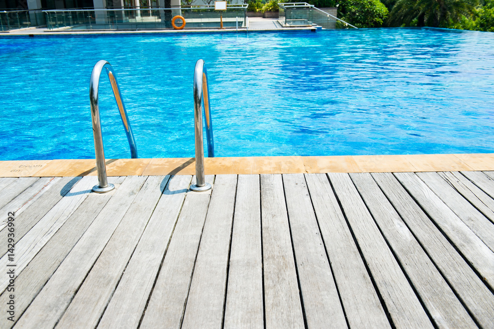 Fototapeta premium Swimming pool with stair and wooden deck at hotel.