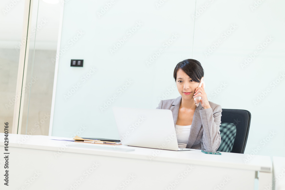 Businesswoman talk to cellphone and working on laptop computer Businesswoman talk to cellphone and working on laptop computer