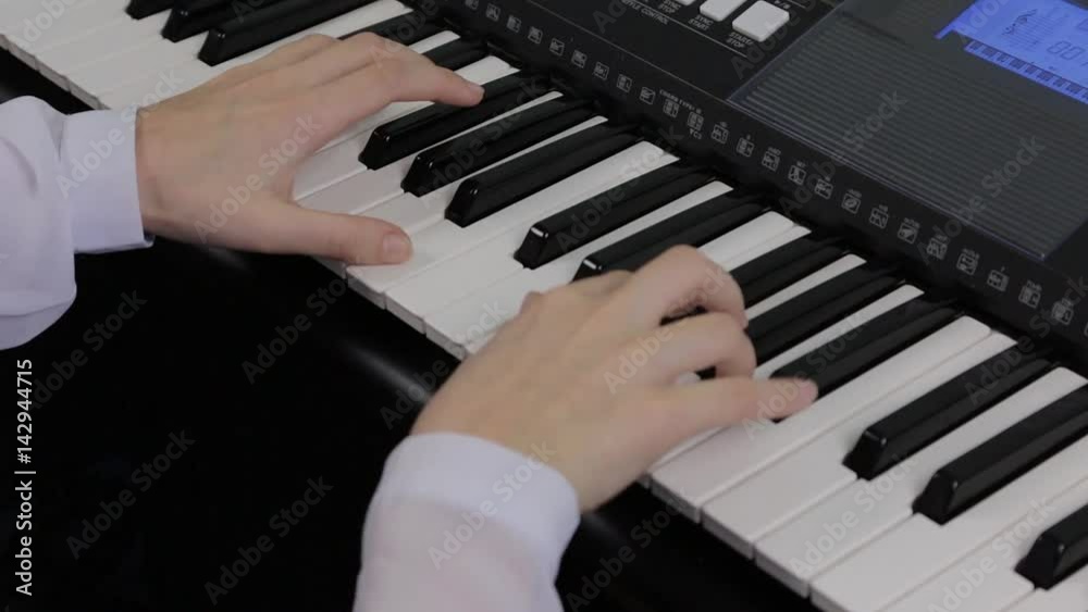 Hands of a teenage girl playing a synthesizer