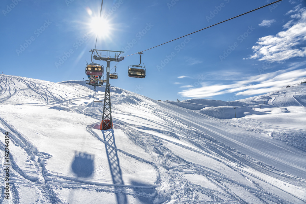 Skiers on the chairlift in high mountains during sunny day