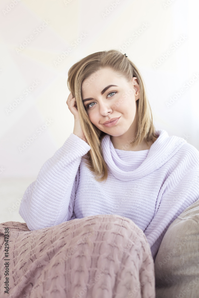 Young pretty blonde girl laying in cozy bed, wearing wool winter sweater happy smiling. Lifestyle people concept Young pretty blonde girl laying in cozy bed, wearing wool winter sweater happy smiling. Lifestyle people concept