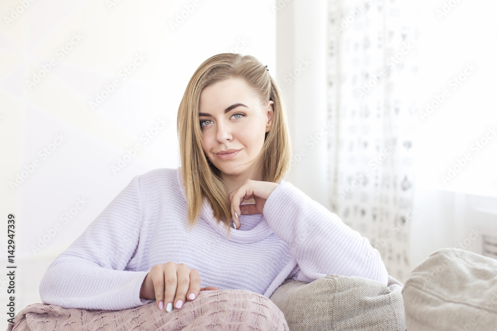 Woman sitting on her sofa in pink pullover Woman sitting on her sofa in pink pullover