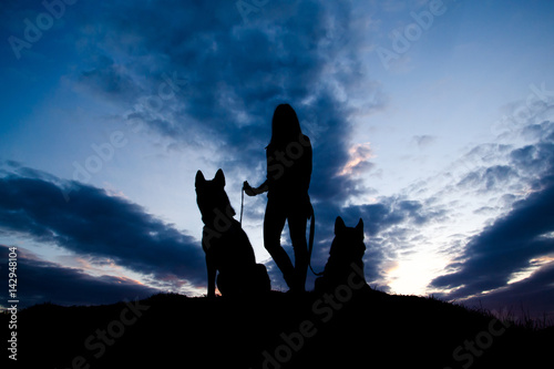 Silhouette of young woman and dog against sky.
