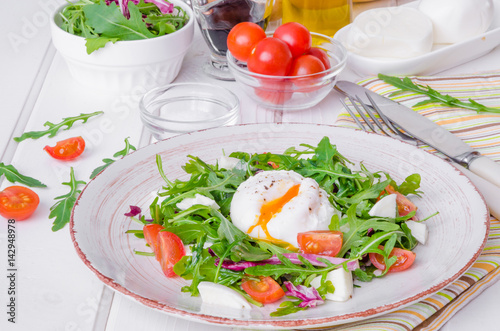 Fresh salad with arugula, mozzarella, cherry tomatoes and poached egg