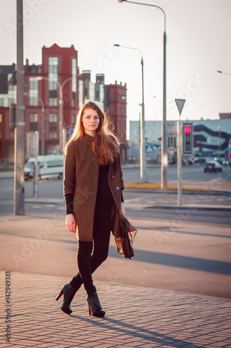 Young attractive girl in a coat in the city at sunset