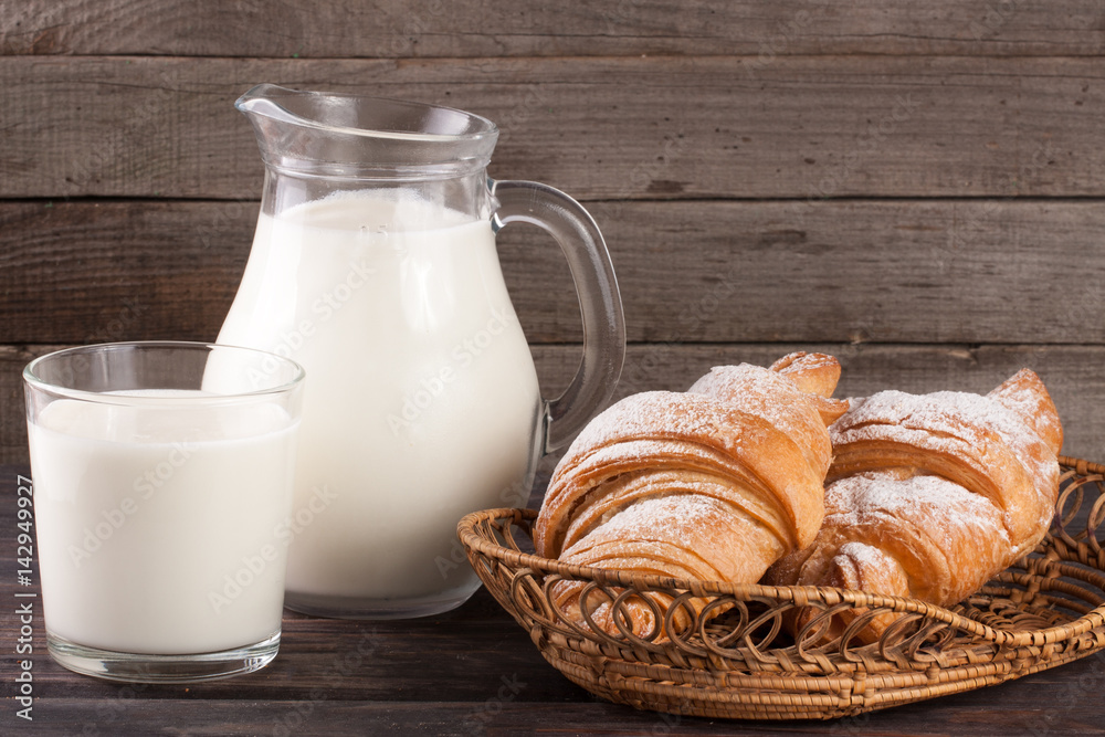 jug and glass of milk with croissants on a wooden background jug and glass of milk with croissants on a wooden background