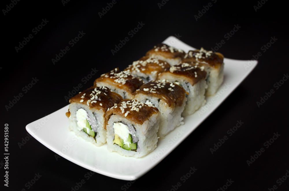 Sushi with eel on white plate on a black background Sushi with eel on white plate on a black background