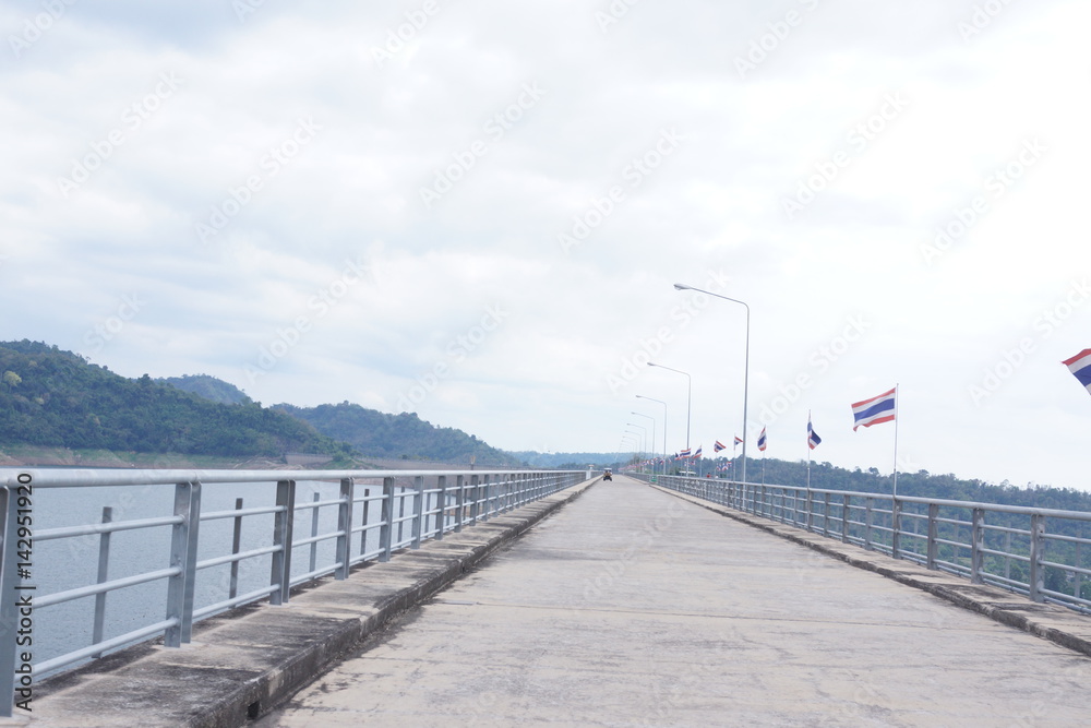 Cement road above the dam with Thai flags.