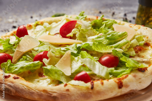 whole italian pizza on wood table with ingredients in black table