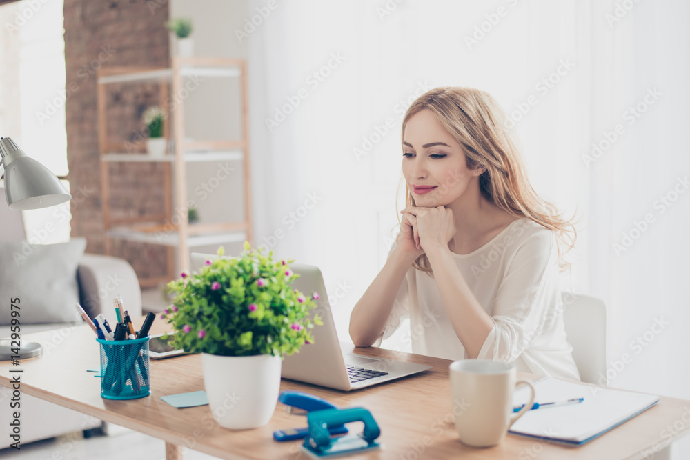 Happy cute pretty woman sitting at the table working with computer at home Happy cute pretty woman sitting at the table working with computer at home