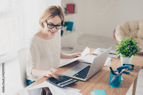 Happy cute  pretty accountant working with computer and calculator photo