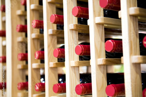 Group of red wine bottles stacked on wooden racks. photo