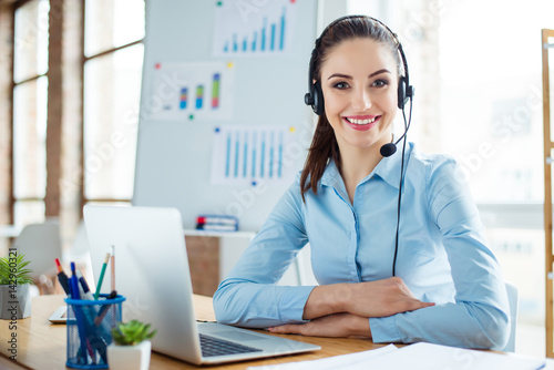 Fotografie Portrait of cute young woman in blue shirt and headphones sitting at the table a