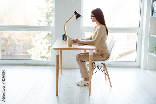 Fotografie Side view portrait of attractive businesswoman in glasses sitting at the table n