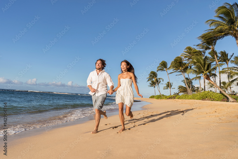 Happy couple relaxing running together having fun during sunset on tropical beach. Summer travel destination.