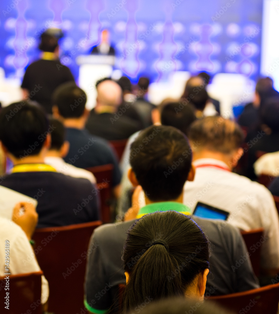 Rear view of business people listening attentively at conference.