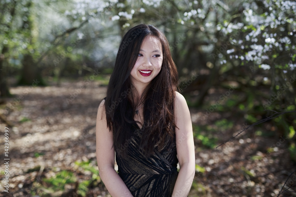 Portrait of a beautiful Chinese, Oriental woman with beautiful eyes and long dark hair posed against a woodland background with blossom trees Portrait of a beautiful Chinese, Oriental woman with beautiful eyes and long dark hair posed against a woodland background with blossom trees