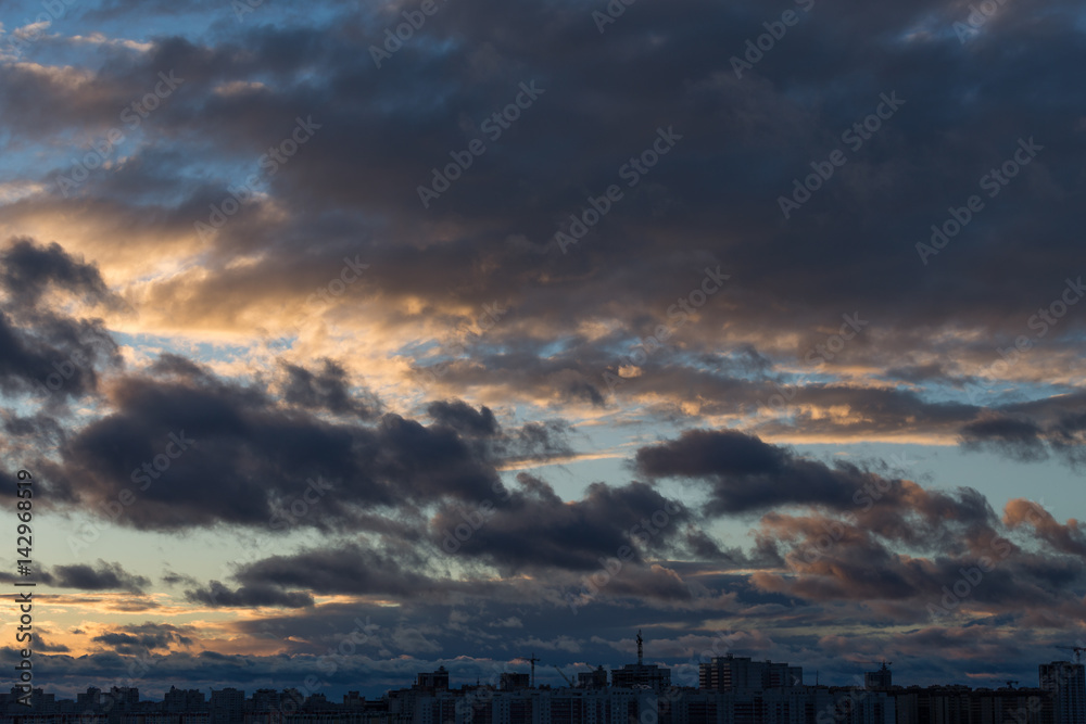 Dramatic cityscape and cloudscape in sunset time with heavy clouds on sky