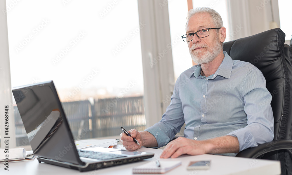 Portrait of businessman sitting in office, hard light Portrait of businessman sitting in office, hard light