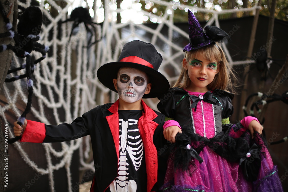 Trick or treat. Trick or treat. Boy in a Halloween costume of skeleton with hat and smocking and a girl with witch costume. Halloween kids