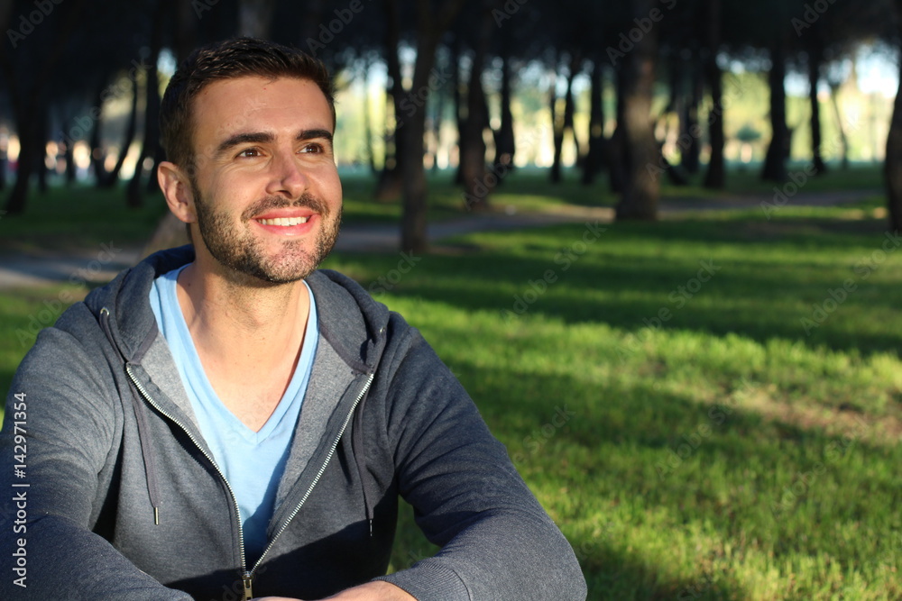 Handsome man smiling in the park while looking at the sunset or sunrise Handsome man smiling in the park while looking at the sunset or sunrise
