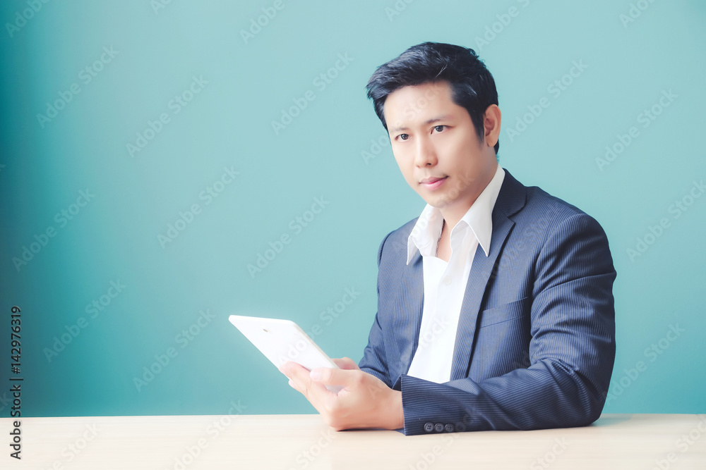 Asian business man using digital tablet while sitting at office table, business and technology Asian business man using digital tablet while sitting at office table, business and technology