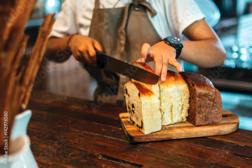 Close up of man hand cutting the bread on the table
