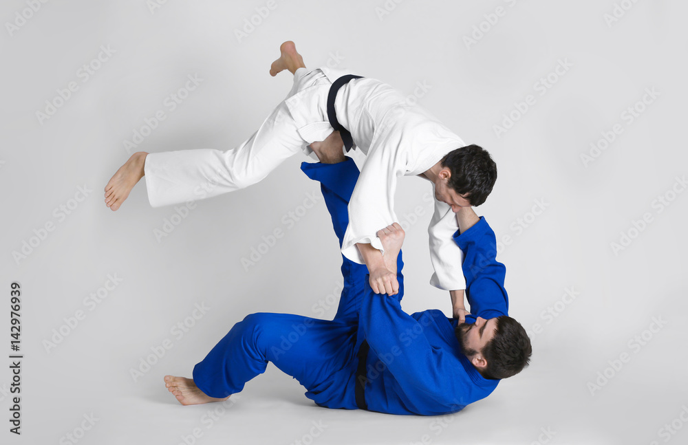 Young sporty men practicing martial arts on light background Young sporty men practicing martial arts on light background