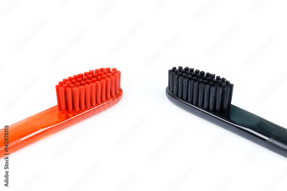 Closeup of two toothbrushes. For men and women. Full black and orange brush. Brush for the family. Isolated on a white background Closeup of two toothbrushes. For men and women. Full black and orange brush. Brush for the family. Isolated on a white background