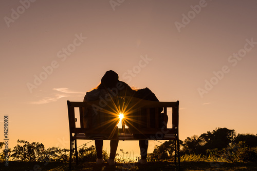 couple site on the wooden chair watch the sun set