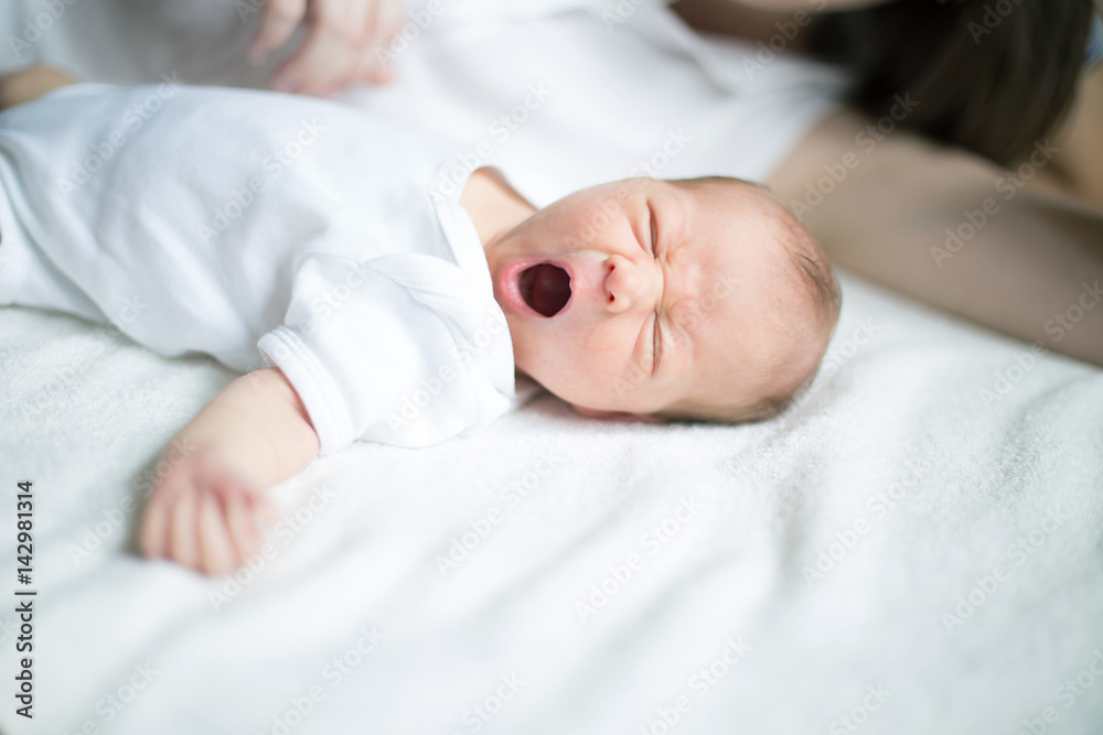 newborn baby lying on the bed and yawns newborn baby lying on the bed and yawns