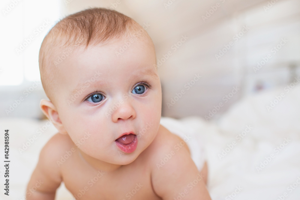 Portrait of cute little infant on a bed in bedroom