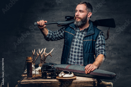 Bearded modernl hunter with his trophy holds a rifle. photo