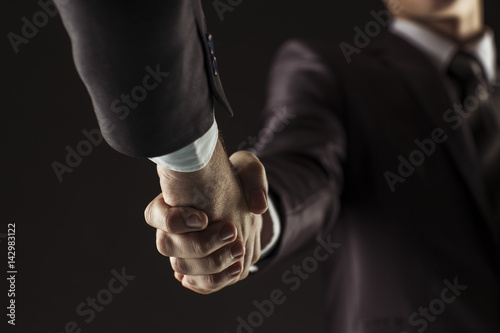 concept of a reliable partnership: a close-up of handshake of business partners on a black background. © yurolaitsalbert