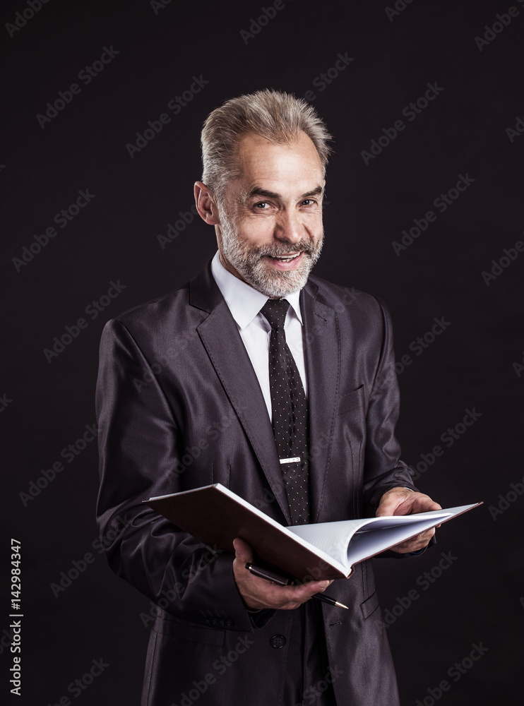 successful businessman with pen and papers ready for signature on a black background successful businessman with pen and papers ready for signature on a black background