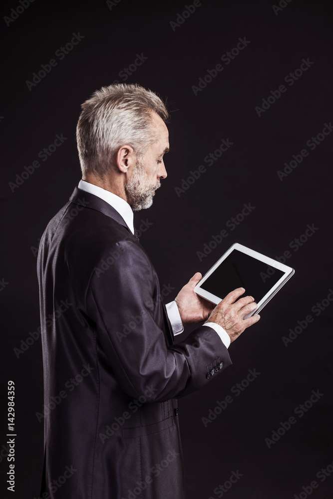 experienced businessman with digital tablet on black background. experienced businessman with digital tablet on black background.