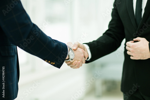 handshake of business partners on background of window in modern