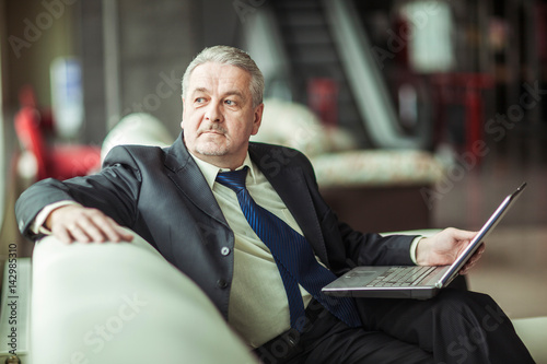 experienced businessman working on laptop sitting on sofa in a private office