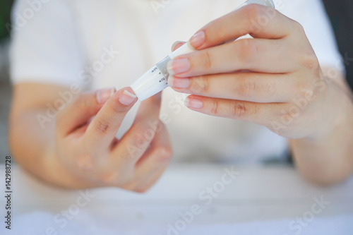 Asian woman hands using lancet on finger to check blood sugar test level by Glucose meter  Healthcare Medical and Check up  Medicine  diabetes  glycemia  health care and people concept