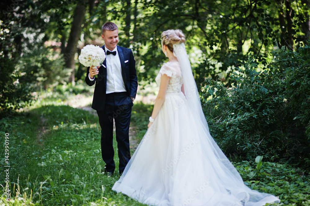 Stylish and gorgeous wedding couple walking outdoor at park on sunny weather.