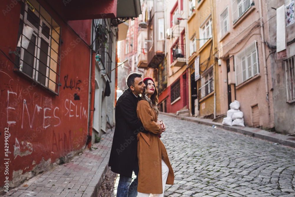 European couple walking at old Istanbul streets. Casual style, red beret and beige coat