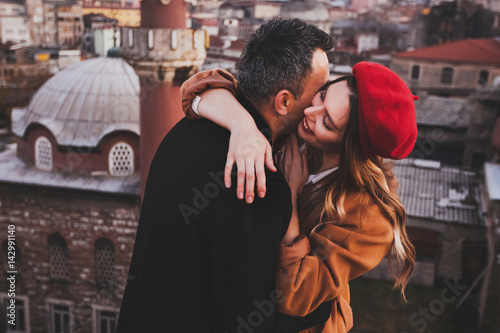 Photography Couple in love hugging on roof with view of evening city at background