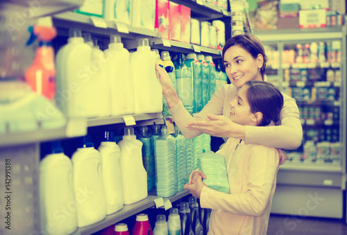 Woman with girl looking for cleaners in supermarket