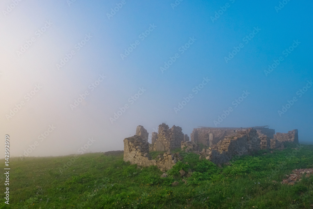 the ruins of the house in the mountains in the early foggy morning
