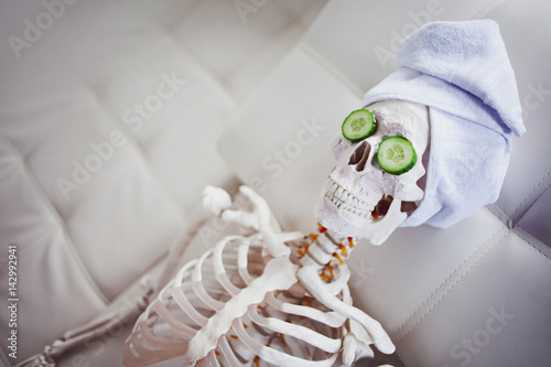 Skeleton in Spa salon with towel on her head and mask on her face, relaxes, care themselves. An absurd concept, social parody. Take care of beauty and forget about inner peace photo