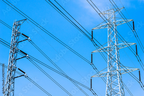 the electricity transmission pylon silhouetted against blue sky