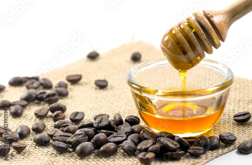 the Honey dipper and fragrant honey into a transparent bowl isolated white background. with coffee bean