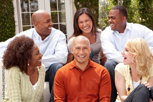 Multi ethnic group of people smiling outside.
