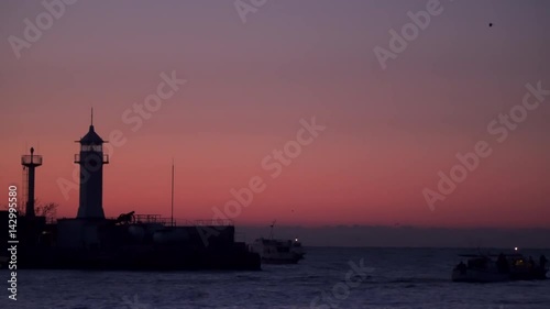 Wallpaper Mural Fishing boats at dawn sail into the sea. They swim past the breakwater with a lighthouse. Yalta Crimea Torontodigital.ca