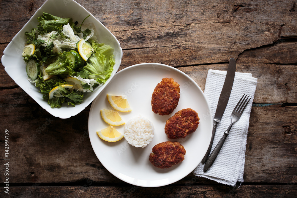 Overhead view of fish crocuettes with fresh green salad. Overhead view of fish crocuettes with fresh green salad.